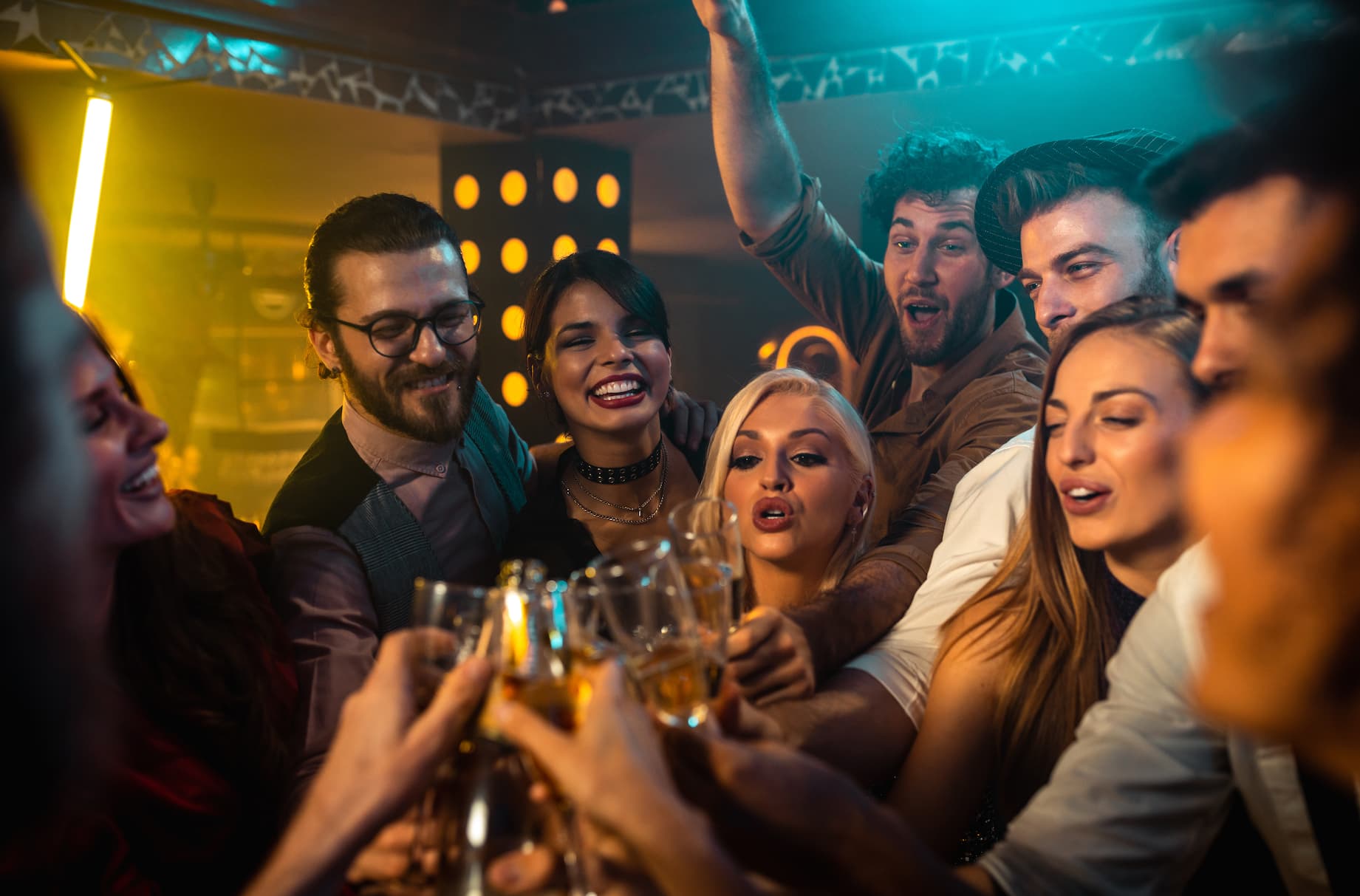 A group of people are standing together, holding wine glasses and toasting. They are all smiling and enjoying the moment.